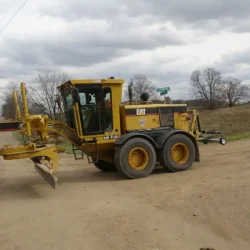 Balayeuse magnétique Erebus suspendue à l'attelage rapide d'une niveleuse